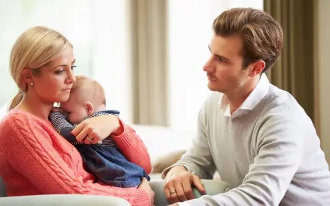 Zmartwiona mama tuli dziecko, a ojciec patrzy z troską. Czy to baby blues? Co to za uczucie?
