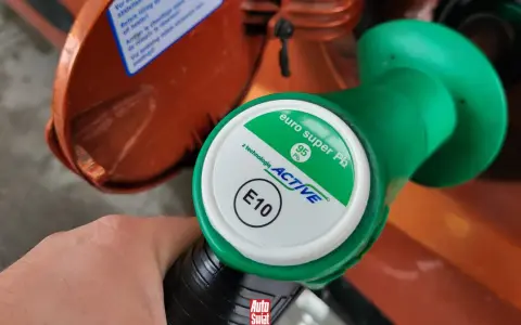 Dłoń trzyma zielony pistolet dystrybutora paliwa z napisem "euro super Pb 95 ACTIVE E10". To paliwo E5, które właśnie tankujesz.