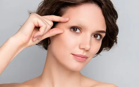 Une femme examine son visage, préoccupée par une possible alopécie sourcil.