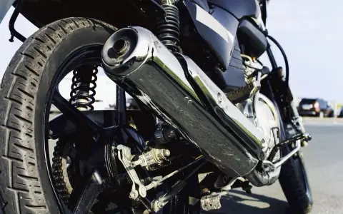Parte trasera de una motocicleta con enfoque en el escape cromado y la rueda.