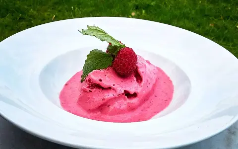 Hallonglass i en vit skål, toppad med hallon och mynta. Perfekt för ett enkelt hallonglass recept.