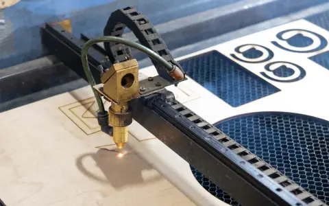 Macchina laser che sta per tagliare compensato, creando forme precise.