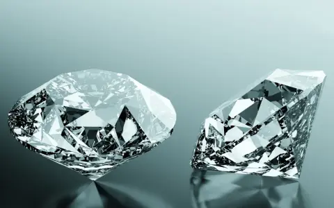 Due diamanti scintillanti, uno rotondo e uno a goccia, riflettono la luce. Uno dei due, un diamante brown, brilla con sfaccettature perfette.