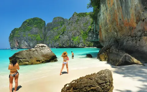 Två personer njuter av det turkosa vattnet och de dramatiska klipporna vid Maya Bay, Thailand.
