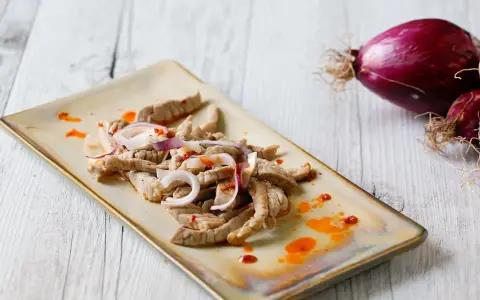 Straccetti di vitello conditi con cipolla rossa e un filo d'olio piccante, pronti per essere gustati.