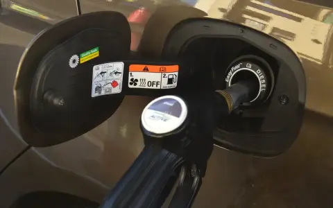 Dozbrań do baku diesla. Pistolet paliwowy wlewa paliwo do samochodu, pokazując, jak zatankować auto.
