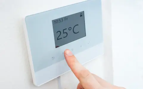Dedo ajustando uno de los tipos de termostatos para calefacción, mostrando 25°C.