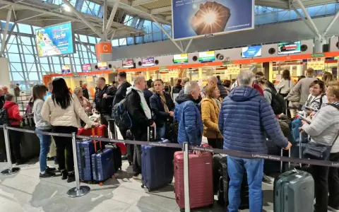 Kolejka do odprawy na jednym z największych lotnisk w Polsce. Pasażerowie z bagażami czekają na swoją kolej.