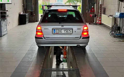Srebrny kombi Honda Civic na podnośniku w warsztacie. Zastanawiasz się, ile kosztuje przerejestrowanie samochodu?