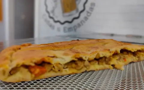 Empanada dorada rellena de carne y verduras. Perfecta para acompañar con una ensalada fresca o una salsa picante.