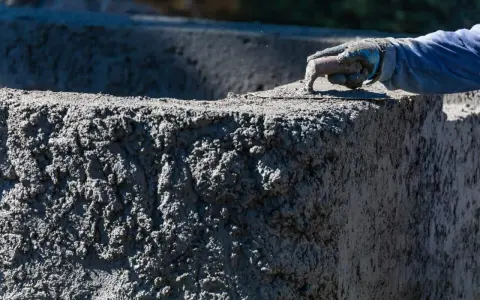 Ręka w rękawicy wygładza świeży beton. Zastanawiasz się, ile kosztuje worek cementu, by stworzyć coś takiego?