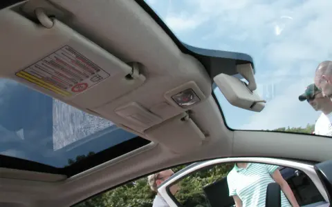 Interior de un Fiat 500 con el techo solar abierto, mostrando el parasol y el espejo retrovisor.
