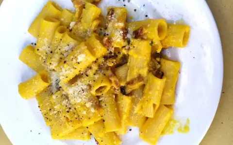 Macarrones con nata, cubiertos de queso rallado y pimienta negra, con trocitos de bacon crujiente.