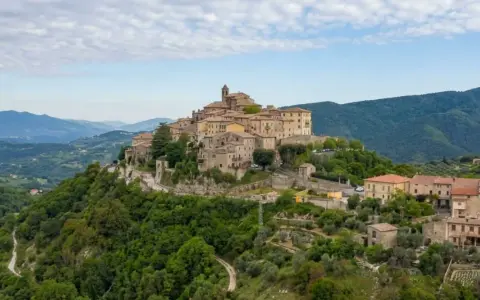 Borgo medievale su una collina verde, uno dei tanti **paesi da vedere vicino Roma**, con case in pietra e un campanile.