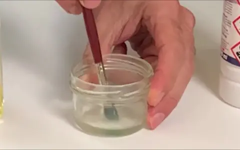 Pincel sumergido en un frasco con disolvente oleo, listo para limpiar.