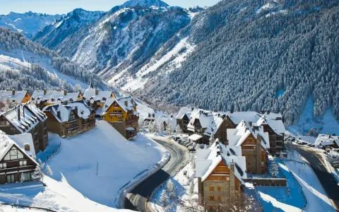Pueblo nevado en los Pirineos, ideal para saber donde ir en el puente de diciembre. Casas de piedra y madera cubiertas de nieve, rodeadas de bosques y montañas.