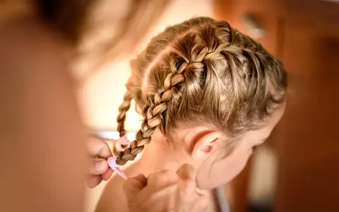 Mama zaplata warkocze. To urocza, krótka fryzura dla dziewczynki, idealna na co dzień.