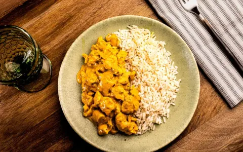 Plato de arroz con pollo en salsa curry, acompañado de arroz blanco. Un delicioso arroz con verduras y proteína.