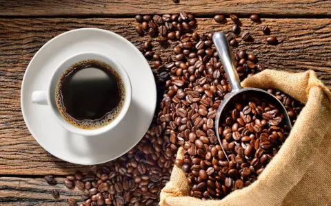 Eine Tasse heißer Kaffee neben einer Schaufel voller gerösteter Bohnen und einem Jutesack. Der Duft von perfekt gebrühtem Filterkaffee liegt in der Luft.