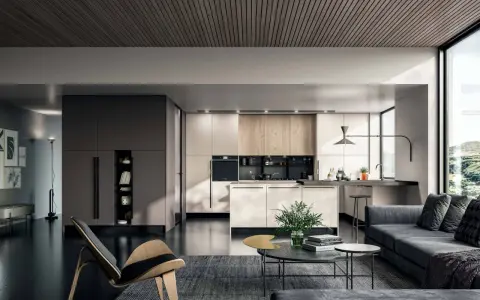 Un elegante appartamento open space moderno con cucina a vista, zona living con divano grigio e poltrona di design.