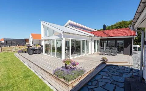 Stor altan med glaspartier och tak, perfekt för sommarkvällar. Kanske krävdes bygglov altan för denna dröm.
