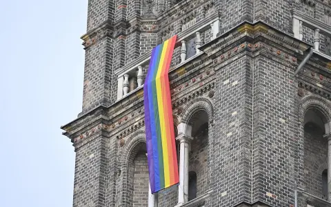 Regenbogenflagge hängt an einer Kirche. Die Bedeutung der Regenbogenflagge steht für Vielfalt und Akzeptanz.