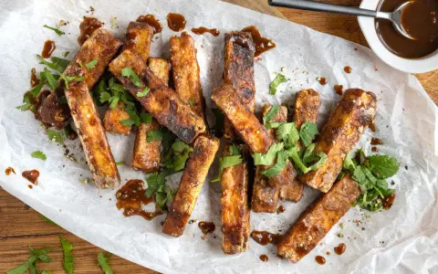 Marinierter Tofu, knusprig gebraten und mit einer dunklen Sauce beträufelt, garniert mit frischem Koriander. Perfekt zum Dippen!
