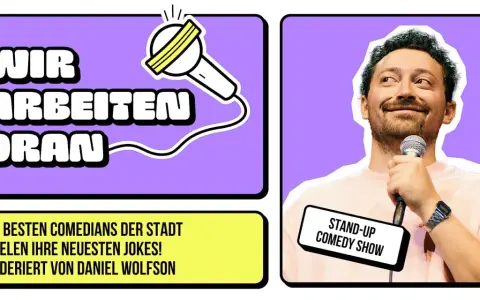 Ein lachender Berliner Comedian hält ein Mikrofon. Daneben steht "Wir arbeiten dran" und "Stand-Up Comedy Show".