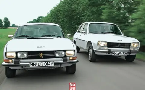 Dwa białe Peugeot 504 jadące obok siebie po wiejskiej drodze.
