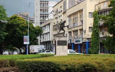 Pomnik żołnierza na tle budynków w Dar es Salaam. W tle widać ruch uliczny i drzewa.