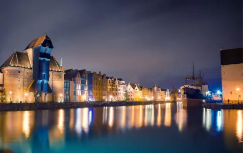 Nocny Gdańsk, Żuraw i zabytkowe kamienice odbijające się w wodzie. Wspaniałe atrakcje pomorskie.