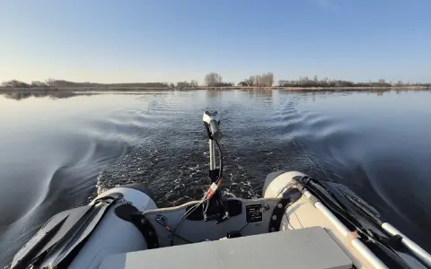 Schlauchboot mit Außenborder auf ruhigem Wasser. Die Beleuchtung des Schlauchboots entspricht der Vorschrift für sicheres Fahren.