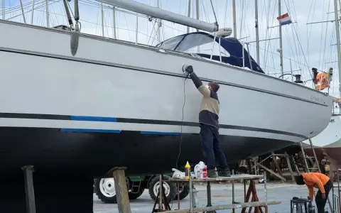 Mann poliert mit Schleifmaschine die Yacht. Edelstahl-Teile glänzen nach der Arbeit.