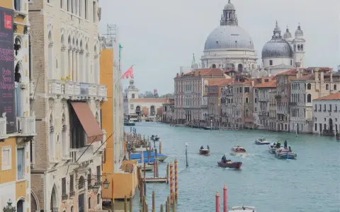 Canali di Venezia, con barche e palazzi storici. Un assaggio di cosa vedere a Venezia in un giorno, tra cupole imponenti e acque azzurre.