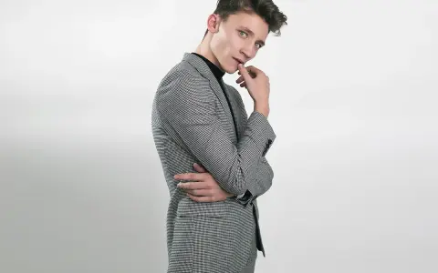 Elegancka stylizacja na 18 urodziny: młody mężczyzna w garniturze w drobną kratkę, czarny golf.