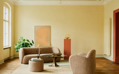 Ein Wohnzimmer mit gelben Wänden und einem frisch gestrichenen, hellgrünen Decke. Gemütliche Bouclé-Möbel und ein moderner Couchtisch laden zum Verweilen ein.