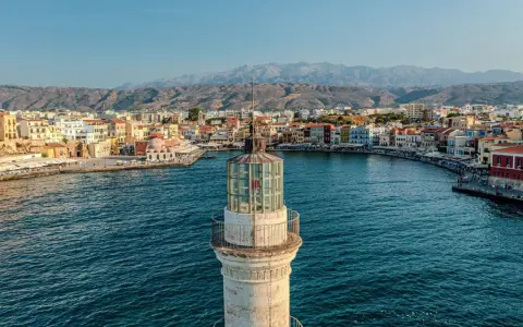 Latarnia morska wenecka w Chanii, prom na Krecie, z widokiem na port i góry w tle.