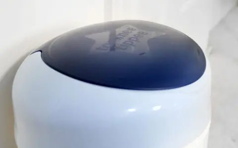 Niebieska pokrywa kosza na pampersy Tommee Tippee z wygrawerowanym logo.