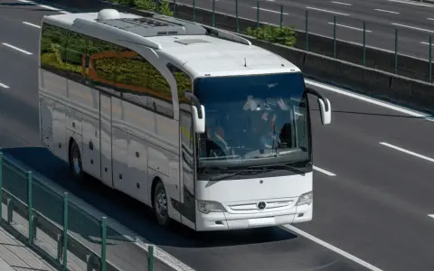 Biały autokar jedzie autostradą. Zastanawiasz się, ile pali bus na 100 km?