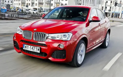 Czerwone BMW X4 w ruchu miejskim. Wady tego modelu mogą dotyczyć widoczności z tyłu i ograniczonej przestrzeni bagażowej.