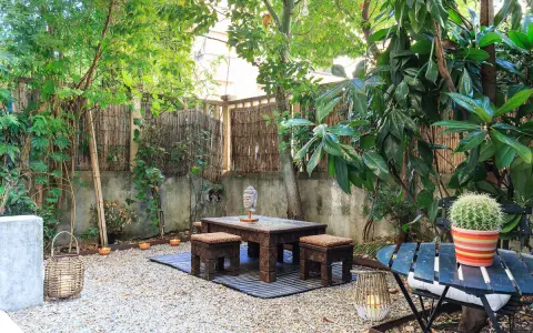 Un angolo relax per il tuo progetto giardino 50 mq: tavolino in legno intagliato, sgabelli, lanterne e un cactus vivace.