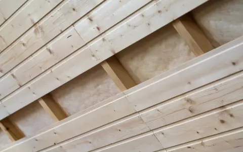 Pose de lambris en bois clair, montrant la structure sous-jacente et l'isolant.