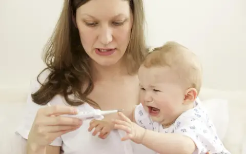 Zmartwiona mama mierzy temperaturę płaczącemu dziecku, które ma gorączkę po szczepieniu.
