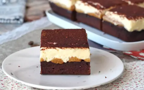Pyszny deser tiramisu przepis. Warstwy czekoladowego ciasta, biszkoptów i kremu, posypane kakao.