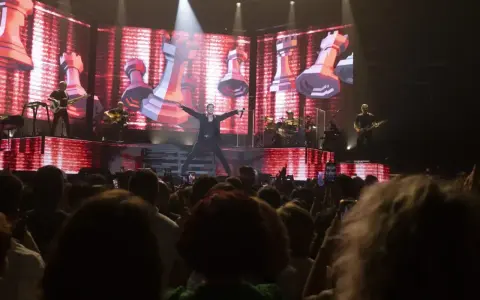 Un cantante en el escenario del 101 music festival, con una pantalla gigante de ajedrez de fondo.