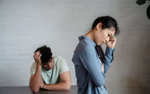 Pareja con expresiones de desánimo, uno con la mano en la cabeza, el otro pensativo. Un reflejo del refuerzo intermitente en la pareja.