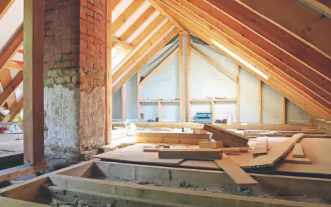 Aménagement des combles : début de la création d'un plancher avec des poutres en bois et des matériaux de construction.