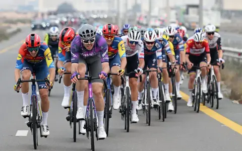 Max Walscheid im violetten Trikot kämpft sich mit anderen Radfahrern durch ein Rennen.
