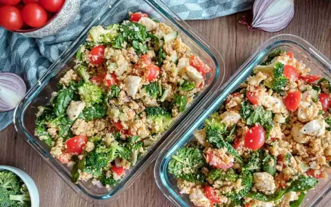 Zwei Behälter mit Couscous-Salat, reich an Couscous-Protein, gefüllt mit Brokkoli, Tomaten, Spinat und Mozzarella.