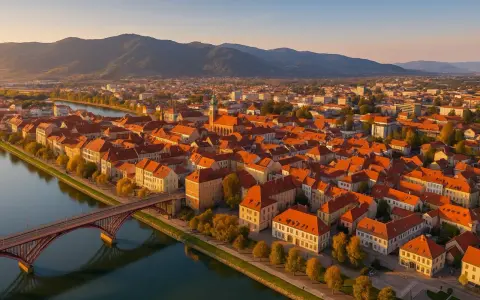 Widok na Maribor z lotu ptaka: rzeka Drava, most, zabytkowe kamienice z czerwonymi dachami i wzgórza w tle. Odkryj mariborskie atrakcje!
